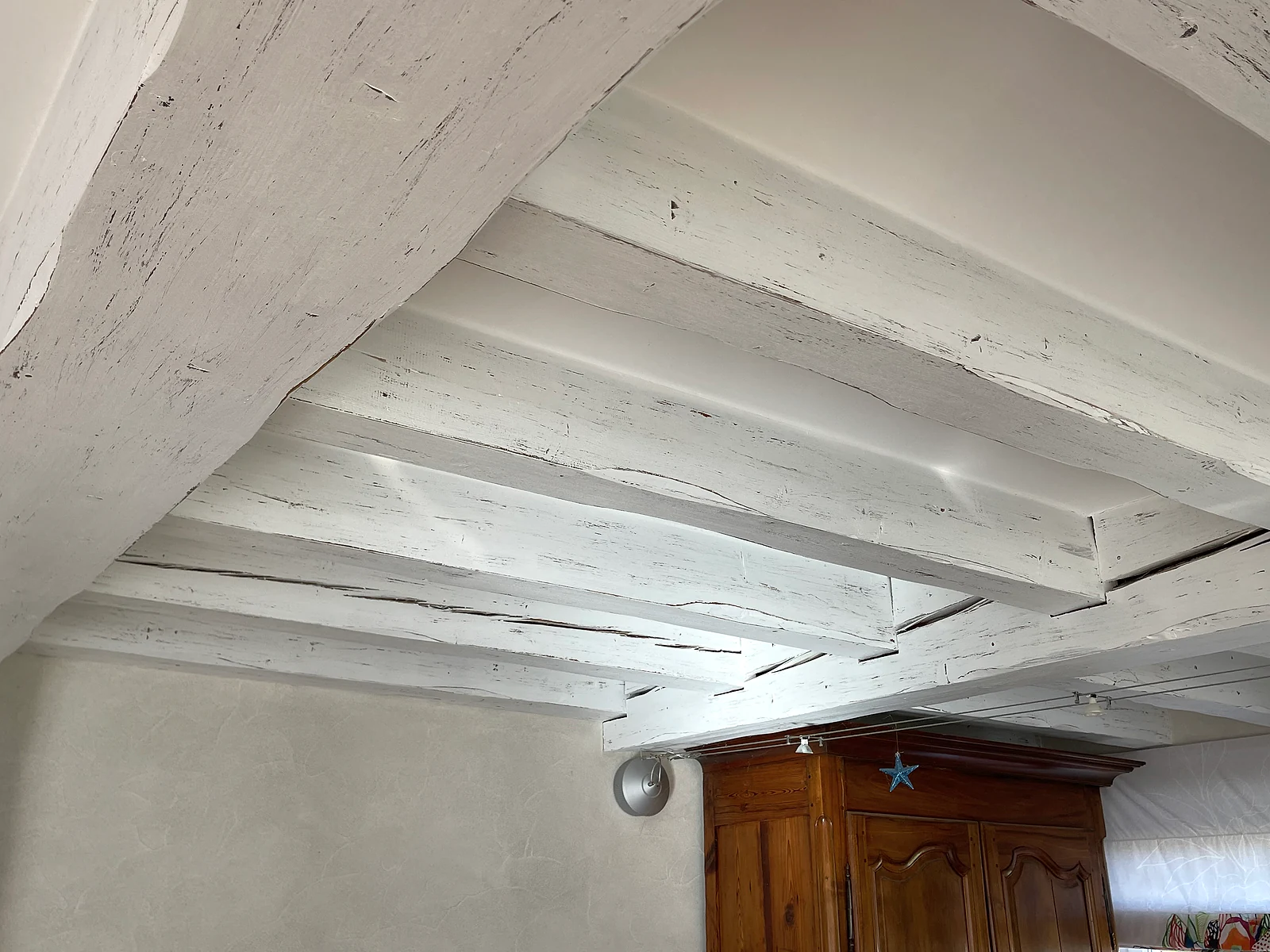 Vue d’ensemble d’un plafond à poutres apparentes avec une finition cérusée blanche